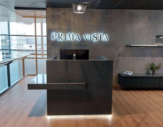 The Prima Vista Lounge reception at Rotterdam The Hague Airport features a sleek counter and visible signage for guest check-in.
