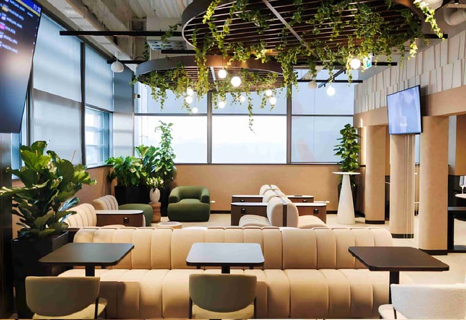 The Business Lounge by Baltona at Rzeszów–Jasionka Airport features comfortable seating areas with tables and greenery for relaxation.