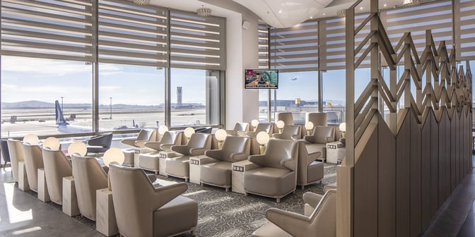 The seating area in Plaza Premium Marmara Lounge offers comfortable chairs with individual tables and airport runway views at Sabiha Gokcen International Airport.