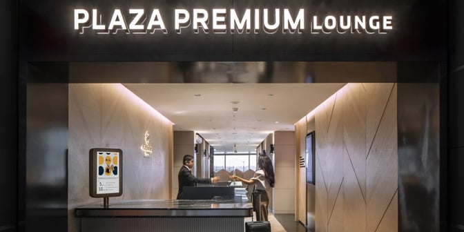 The entrance to the Plaza Premium Lounge at Sabiha Gokcen Airport features a reception desk and signage for guest assistance.
