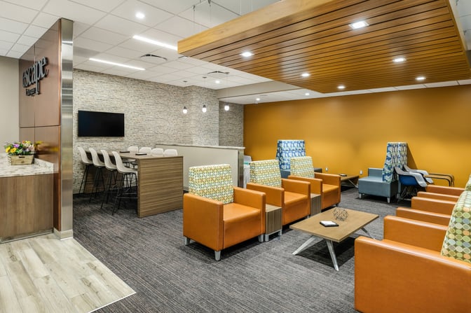 The seating area in the Escape Lounge at Sacramento International Airport features comfortable chairs and a communal table with barstools.