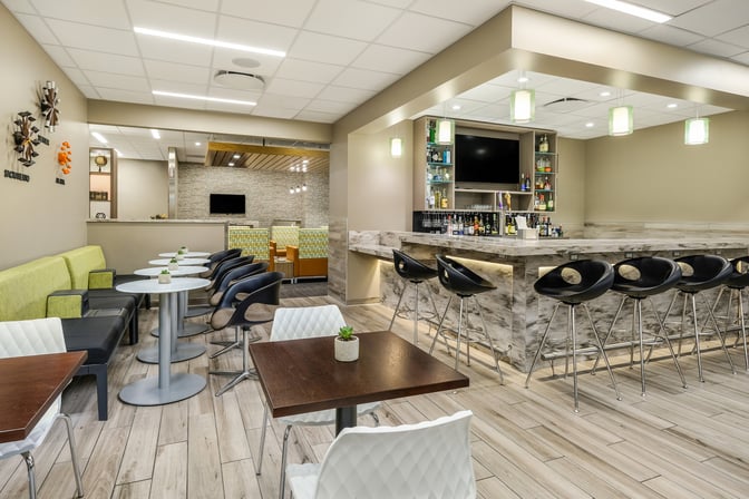 The Escape Lounge at Sacramento International Airport features a bar with seating and a dining area with tables and chairs.