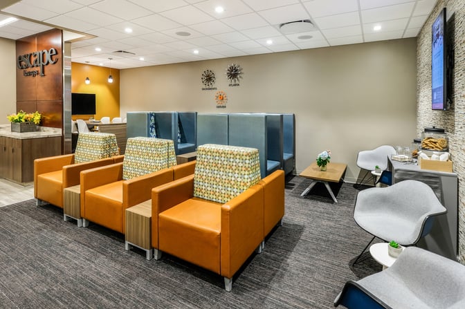 The Escape Lounge at Sacramento International Airport features comfortable seating areas with armchairs and booths, offering a relaxing space for travelers.