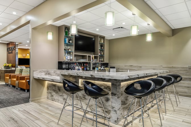 The Escape Lounge at Sacramento International Airport features a bar with a variety of spirits and seating for guests.