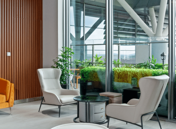 The seating area in Angkor Lounge at Siem Reap–Angkor International Airport features armchairs and a small table near large windows.