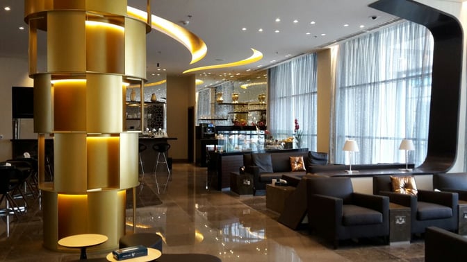 The Oman Air Al Khareef Lounge at Salalah Airport features comfortable seating and a bar area with high stools and refreshments.