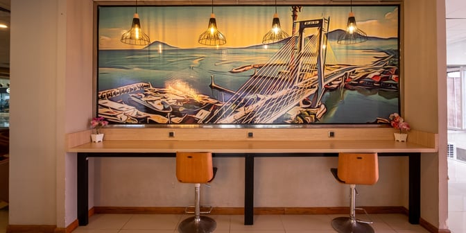 The Concordia Lounge at Sam Ratulangi International Airport features a work area with counter seating and power outlets beneath a large mural.