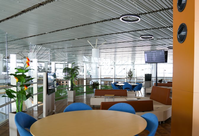 The CIP Lounge at Samarkand International Airport features seating areas with tables, chairs, and a flight information display screen.