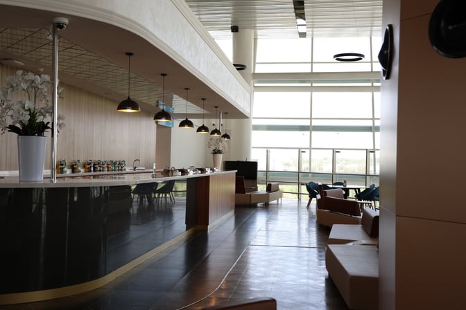 The CIP Lounge at Samarkand International Airport features a bar area with complimentary beverages and seating with airport views.
