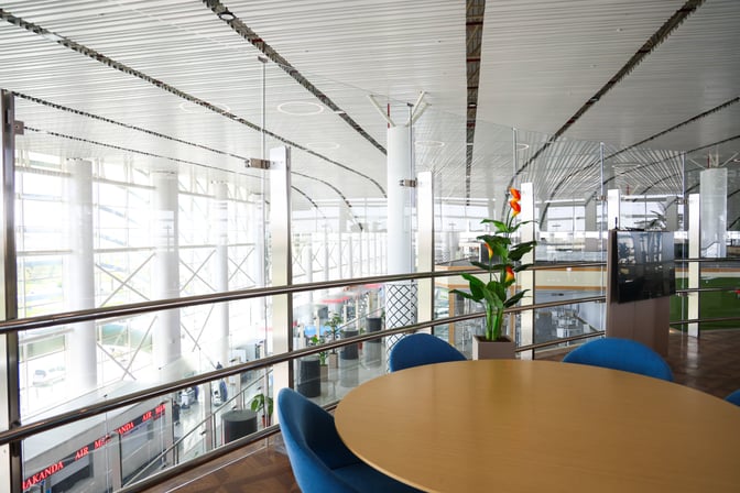 The CIP Lounge at Samarkand International Airport features a seating area with a round table and views of the terminal.