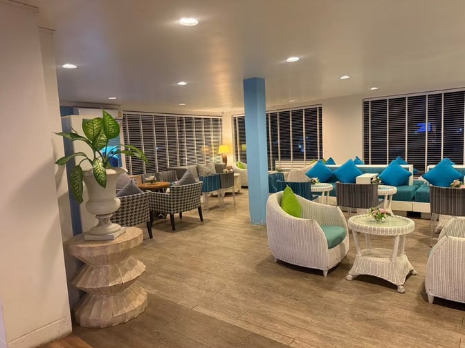 The seating area in Bangkok Airways Blue Ribbon Lounge at Samui International Airport features wicker chairs and tables for passenger relaxation.