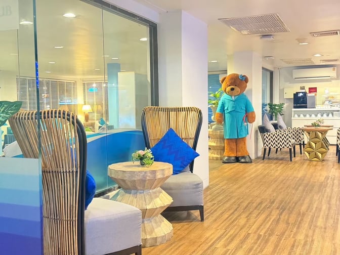 Seating area in Bangkok Airways Blue Ribbon Lounge at Samui Airport features comfortable chairs, small tables, and a decorative bear figure.