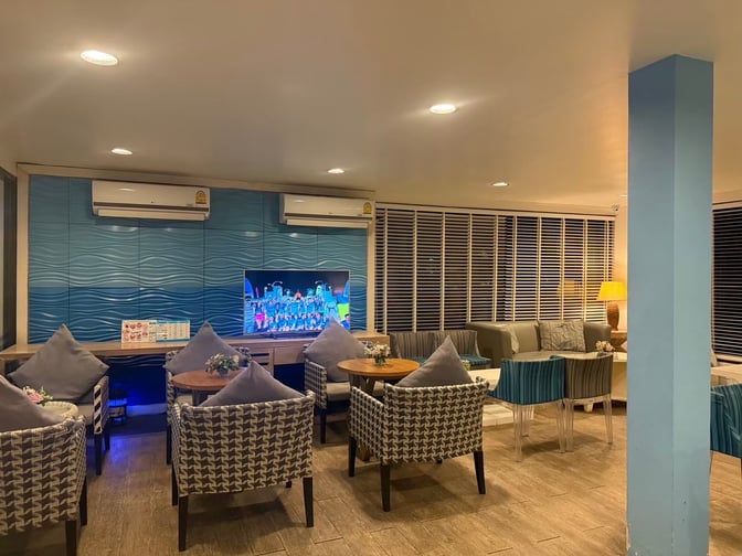 The seating area in Bangkok Airways Blue Ribbon Lounge at Samui International Airport features cushioned chairs, a television, and tables for relaxation.