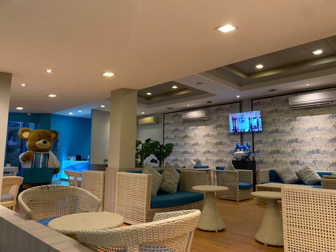 The Bangkok Airways Blue Ribbon Lounge at Samui International Airport features wicker seating and a television for passenger relaxation.