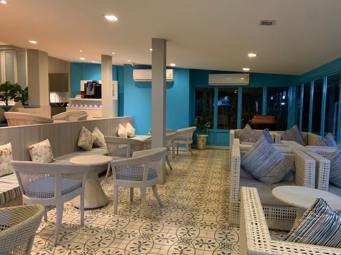 The seating area in Bangkok Airways Blue Ribbon Lounge at Samui International Airport features wicker chairs and tables with cushioned seating.