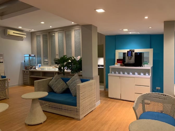 The Bangkok Airways Blue Ribbon Lounge at Samui International Airport features a seating area with wicker furniture and a self-serve coffee station.