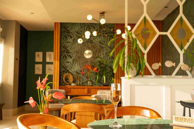 The seating area in Magma Lounge at San Cristóbal Airport features tables with reserved signs and decorative plants.