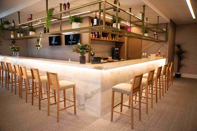 The W Lounge bar at Goiânia International Airport features a marble counter with high seating and a selection of displayed beverages.