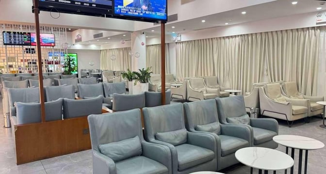 The seating area in China Southern Lounge at Sanya Phoenix International Airport features comfortable chairs and tables with flight information screens.