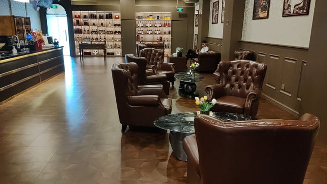 The Cuba Pavilion Lounge at Sanya Phoenix International Airport features leather armchairs and marble tables, with a bar and display shelves.