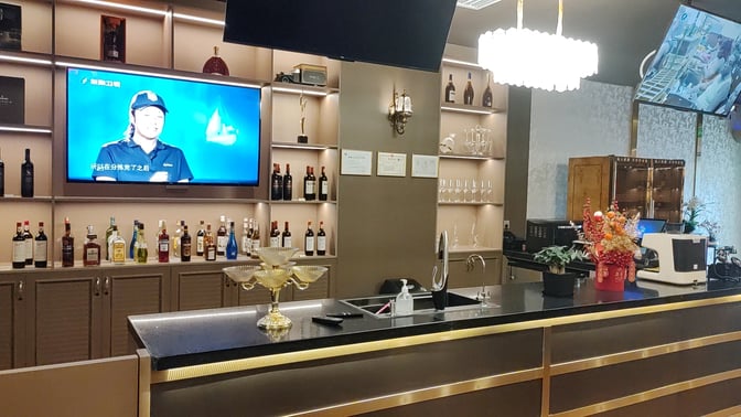 The bar at the Cuba Pavilion Lounge in Sanya Phoenix International Airport features a selection of spirits and a television.