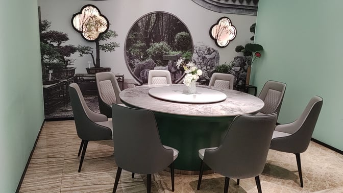 A round table with seating for eight is set in a private area, featuring decorative wall art at Sanya Phoenix International Airport.