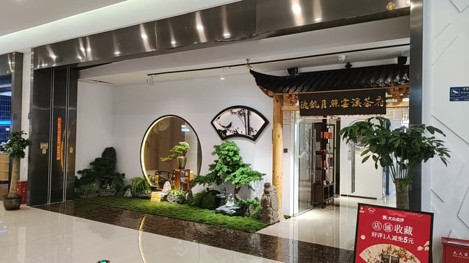 The entrance to Dehang Moonlight Yunxi Tea House at Sanya Phoenix International Airport features decorative plants and traditional architectural elements.