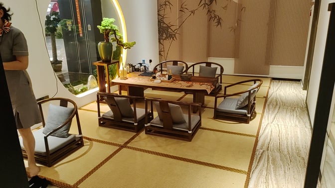 The tea house seating area features a low wooden table with cushioned chairs, offering a traditional tea service setup.