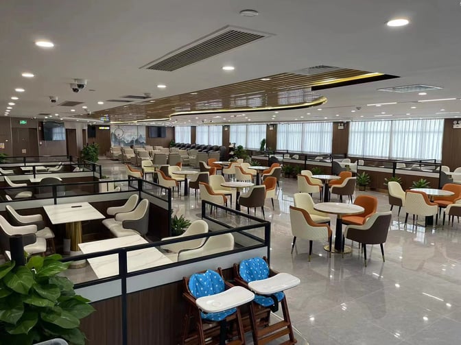 The V1 First Class Lounge at Sanya Phoenix International Airport features spacious seating areas with tables and chairs for dining and relaxation.