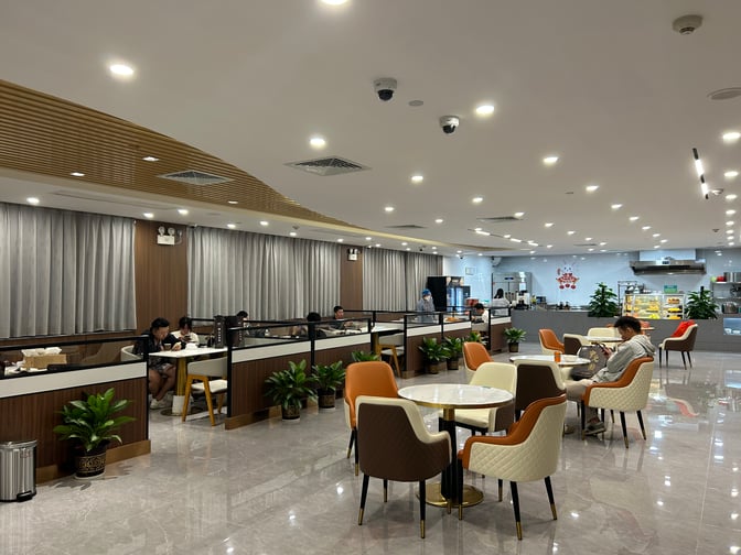 The V1 First Class Lounge at Sanya Phoenix International Airport features a seating area with tables and a self-serve food station.