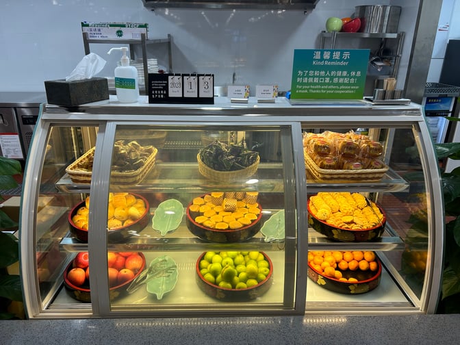 The food display at V1 First Class Lounge in Sanya Phoenix International Airport offers a selection of fruits, pastries, and packaged snacks.