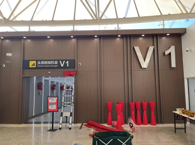 The entrance to the V1 First Class Lounge at Sanya Phoenix International Airport features a sign and a partially open door.