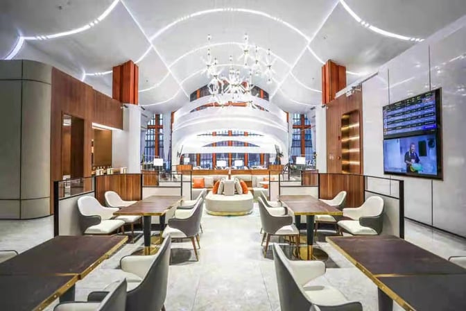 The V3 First Class Lounge at Sanya Phoenix International Airport features a spacious seating area with tables, chairs, and a large display screen.