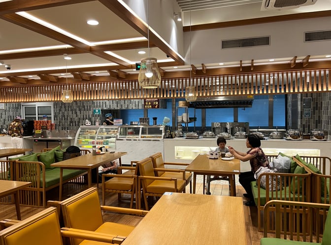 The V2 First Class Lounge at Sanya Phoenix International Airport features a dining area with self-serve food stations and seating.