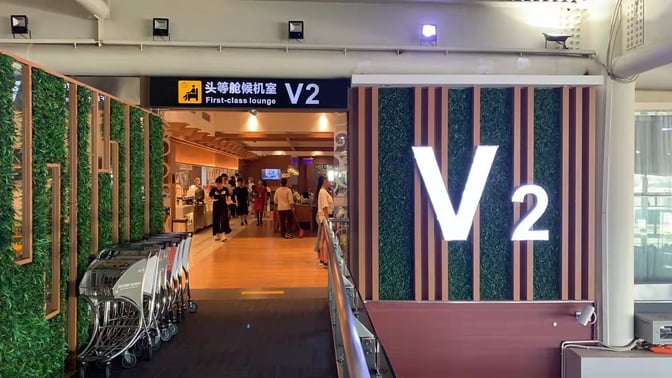 The entrance to the V2 First Class Lounge at Sanya Phoenix International Airport features a prominent sign and visible interior activity.