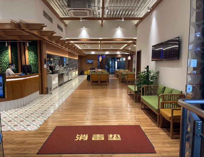 The V2 First Class Lounge at Sanya Phoenix International Airport features a reception desk, seating area, and a display screen for flight information.