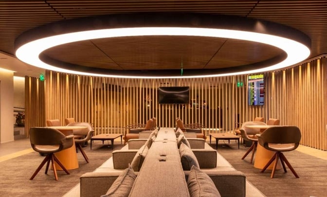 The seating area at Plaza Premium Lounge in Sao Paulo–Guarulhos Airport features comfortable chairs, sofas, and a central television for relaxation.