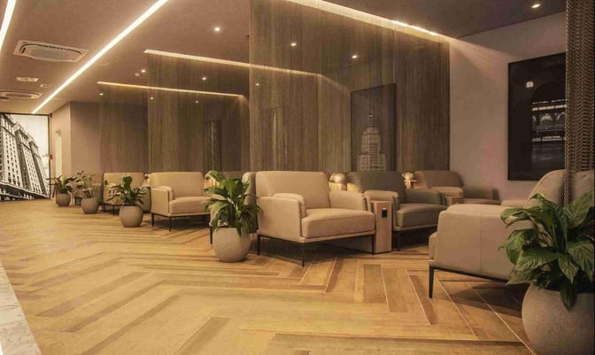 The seating area at W Lounge Guarulhos features comfortable armchairs and potted plants, providing a relaxing space for travelers.