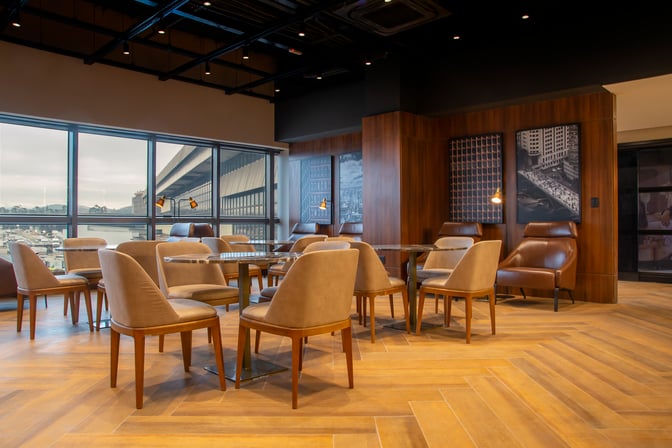The seating area in W Lounge Guarulhos features tables and chairs with airport views through large windows.