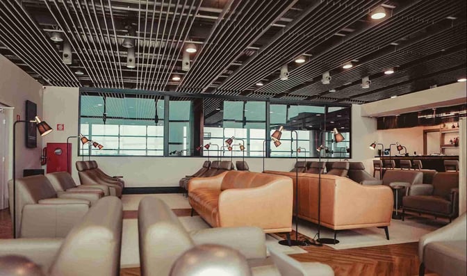 The W Premium Lounge at Guarulhos Airport features comfortable seating with individual lamps and a bar area for refreshments.