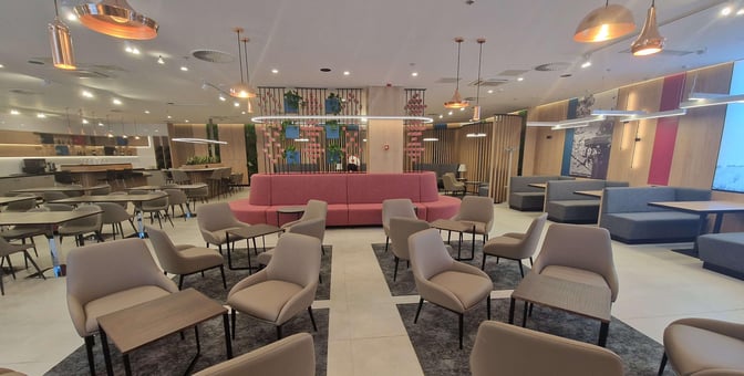 The business lounge at Sarajevo International Airport features a variety of seating options, including chairs and booths, with a central seating area.