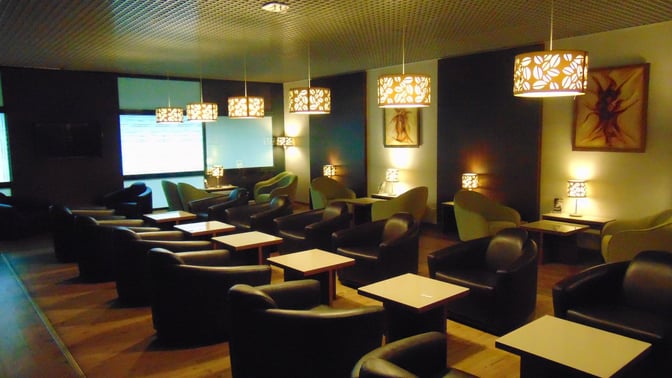 The seating area in Sarajevo International Airport's business lounge features armchairs and small tables, providing a comfortable space for travelers.