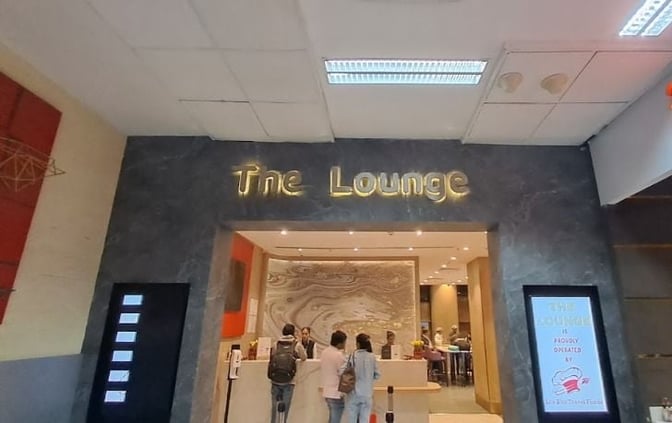 The entrance to The Lounge at Sardar Vallabhbhai Patel International Airport features a reception desk and visible seating area inside.