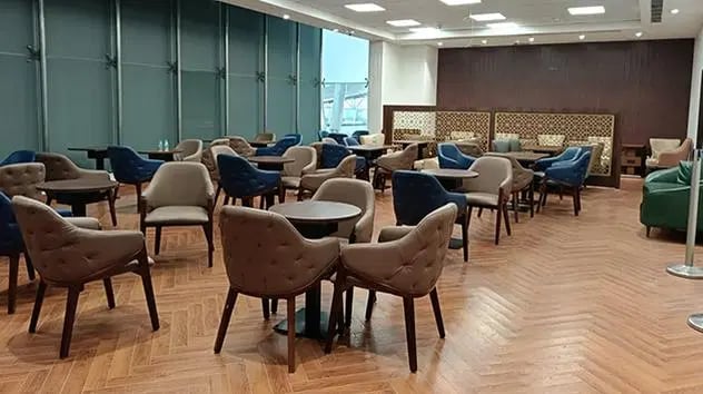 The seating area at The Lounge Terminal 2 Sardar Vallabhbhai Patel International Airport features tables and chairs arranged for passenger relaxation and dining.