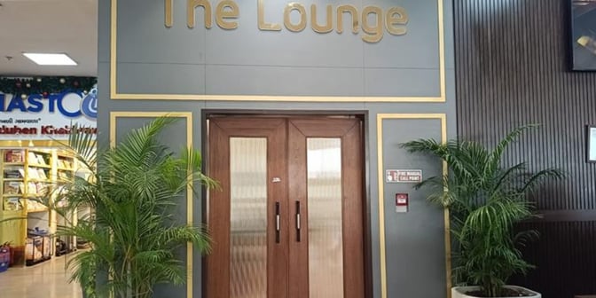 The entrance to The Lounge Terminal 2 at Sardar Vallabhbhai Patel International Airport features double doors flanked by potted plants.