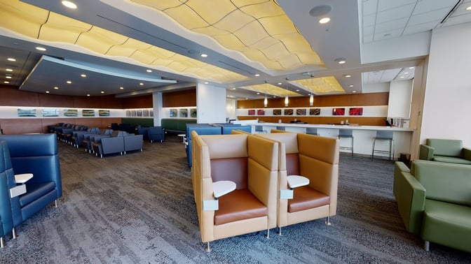 The Club SEA at Seattle-Tacoma International Airport features semi-private seating with individual tables and a bar area with high stools.