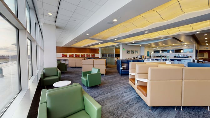 The Club SEA lounge at Seattle-Tacoma International Airport features spacious seating areas with views of the runway and a bar area.