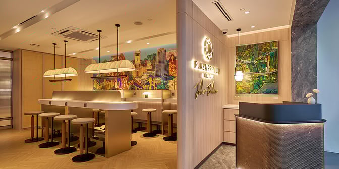 The Plaza Premium Lounge at Senai International Airport features a seating area with bar-style stools and a vibrant mural backdrop.