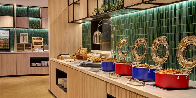 The Plaza Premium Lounge at Senai International Airport features a self-serve food area with hot dishes and snacks available.