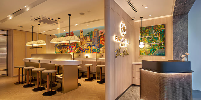 The Plaza Premium Lounge at Senai International Airport features a seating area with bar-style stools and a vibrant mural backdrop.